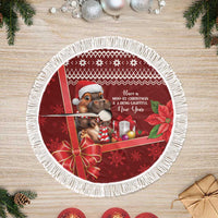 Red round Christmas tree skirt with fringe border, cartoon cow in hat, poinsettia accents