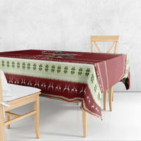 Red holiday tablecloth draped over table with green leaf and Santa figures