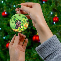 Green circular St. Patrick's Day ceramic ornament held by hand; cartoon bear, clovers, coins.
