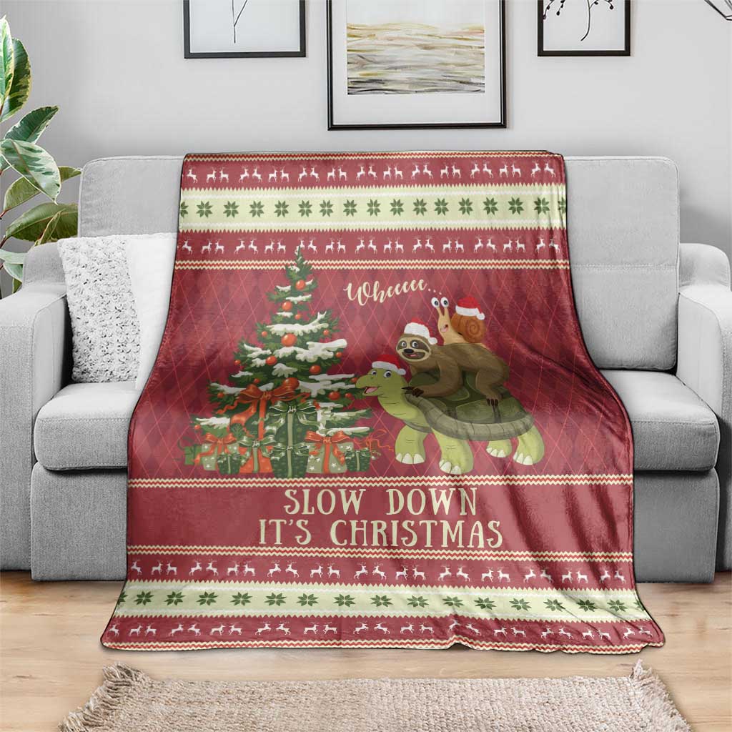 Red Christmas throw blanket draped on couch with sloth turtle ride graphic and patterned trim