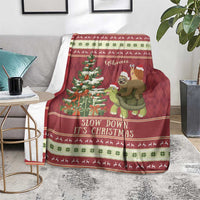 Red Christmas throw blanket laid across sofa with sloth turtle ride scene and festive trim
