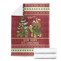 Red Christmas throw blanket folded with sloth riding turtle graphic and decorative border