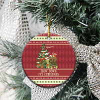 Red circular ceramic Christmas ornament with sloth and snail on turtle; on evergreen branches