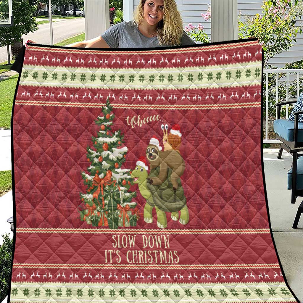 Red Christmas quilt spread outdoors, showing sloth riding turtle, Christmas tree, and border stripes.