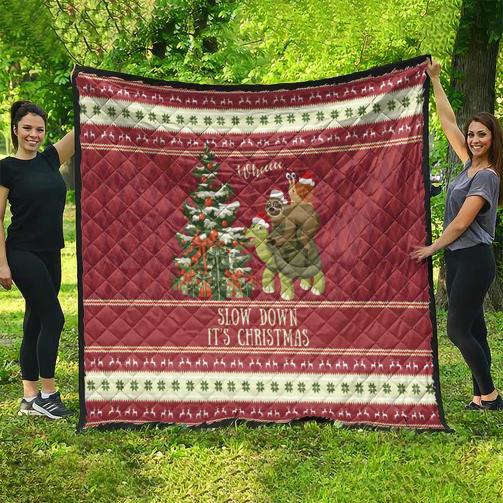 Red quilt outdoors featuring sloth riding turtle beside Christmas tree and patterned holiday trim.