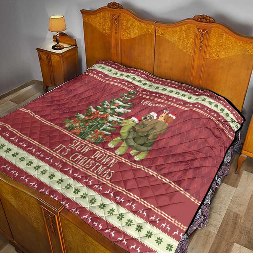 Red Christmas quilt on bed with sloth riding turtle; “Slow down it’s Christmas” text and border.