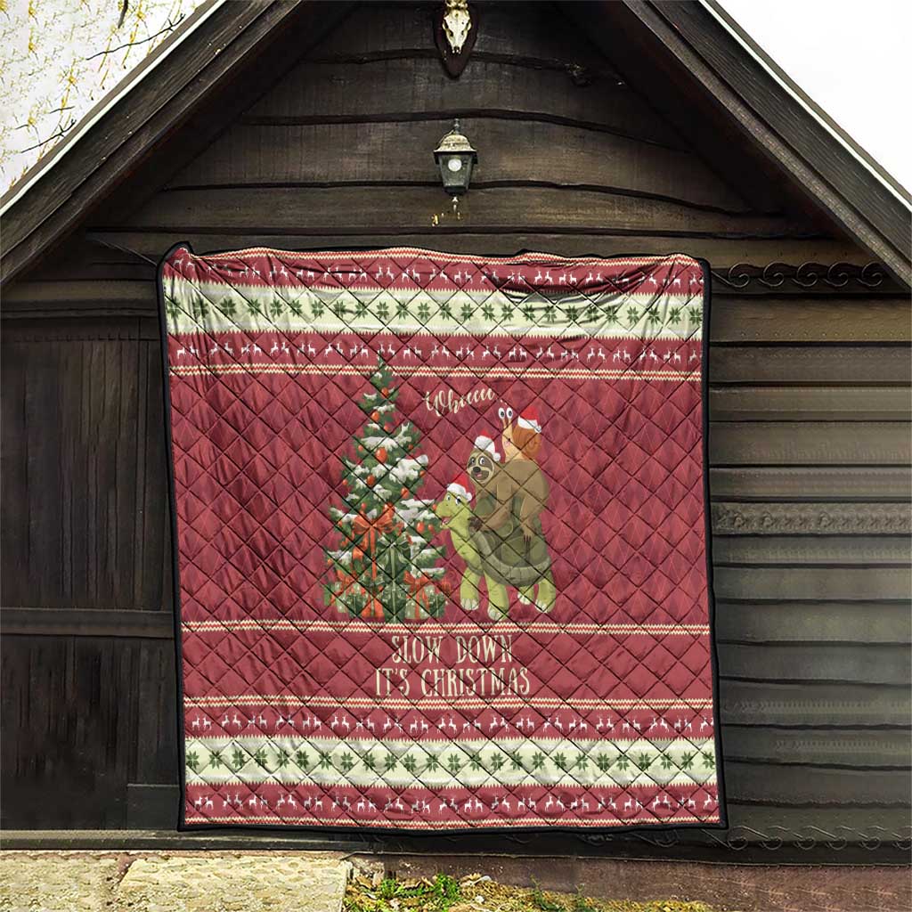 Red quilt hanging under a porch roof with sloth-and-turtle Christmas scene and “Slow down” text.