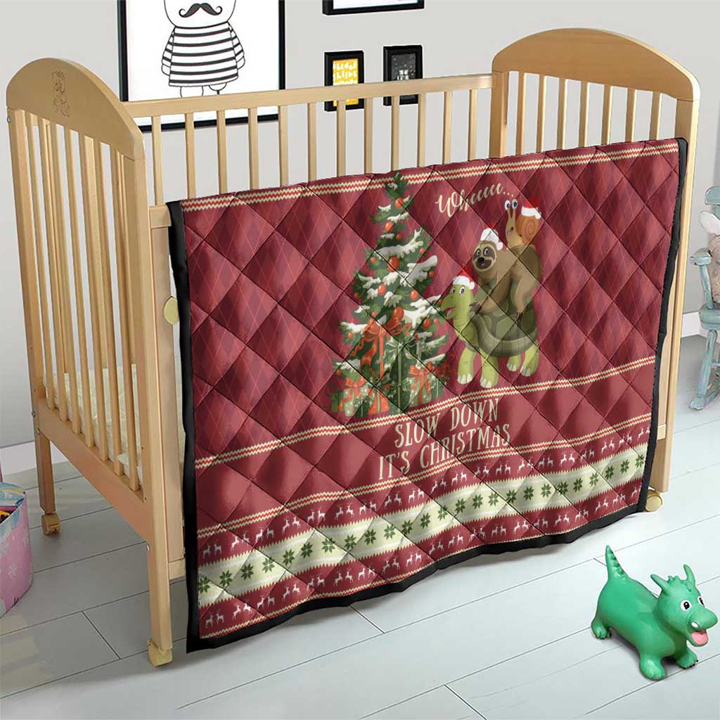Red quilt on crib with sloth riding turtle artwork and “Slow down it’s Christmas” text.