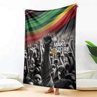Black crowd blanket with green, yellow, and red stripe header and “MAKE HISTORY Her” text