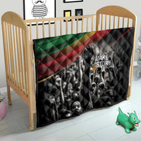 Black quilt in baby crib with Pan-African diagonal stripe and 'MAKE HISTORY Her' text