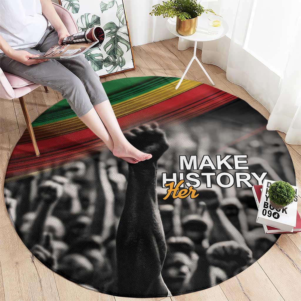 Round black carpet with Make Her text; feet stepping on crowd graphic with green/red stripes