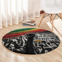 Round black carpet with Make History Her text, crowd graphic, green and red stripe border