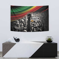 Black tapestry with multicolor top stripes, raised fist over crowd, 'Make History' text