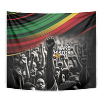 Black tapestry wall hanging close view: raised fist over crowd, multicolor stripe band