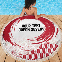 Round beach blanket with red rising sun swirl on white, fringe border visible