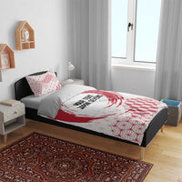 Red and white duvet on dark bed frame with matching pillowcases, emblem, and geometric pattern