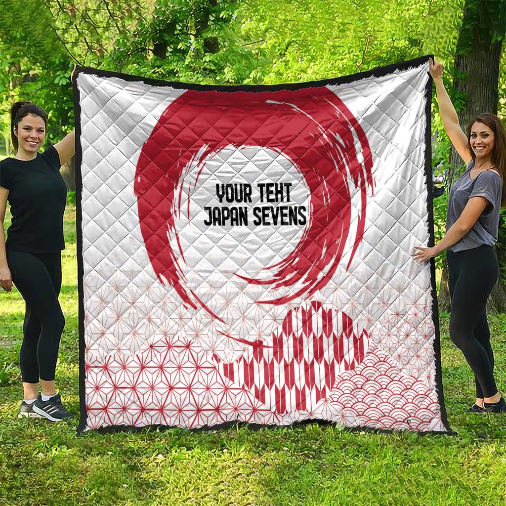 White quilt spread outdoors with red rising sun, hex lines, and wave pattern at bottom.