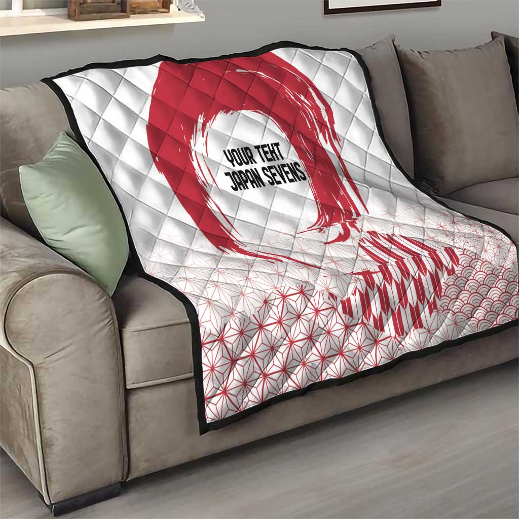 White quilt on a sofa with red rising sun and geometric pattern; partial waves at the corner.