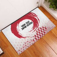 White rubber doormat shown indoors on wood floor, red circular rising sun graphic