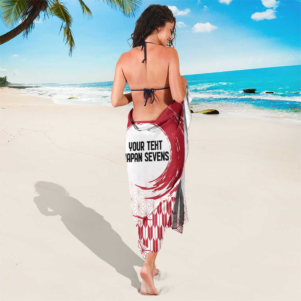 White sarong with red circular graphic and repeating fan/diamond pattern, printed text