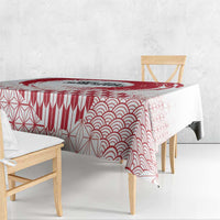 Red and white tablecloth with wave and geometric fan patterns draped over dining table