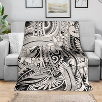 Tribal polynesian print throw blanket draped on gray sofa, black-and-white floral design