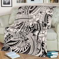 Tribal polynesian print throw blanket laid across sofa, bold black-and-white floral motifs