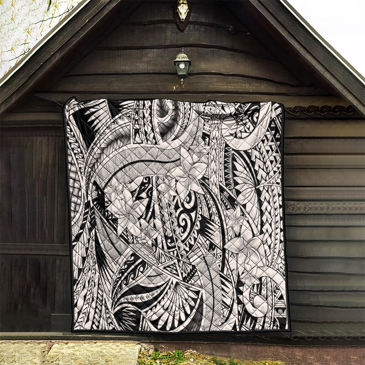 Tribal black-and-white quilt blanket displayed on a wooden wall backdrop