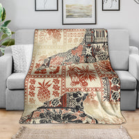 Beige throw blanket with red and black tribal motifs, spread across sofa
