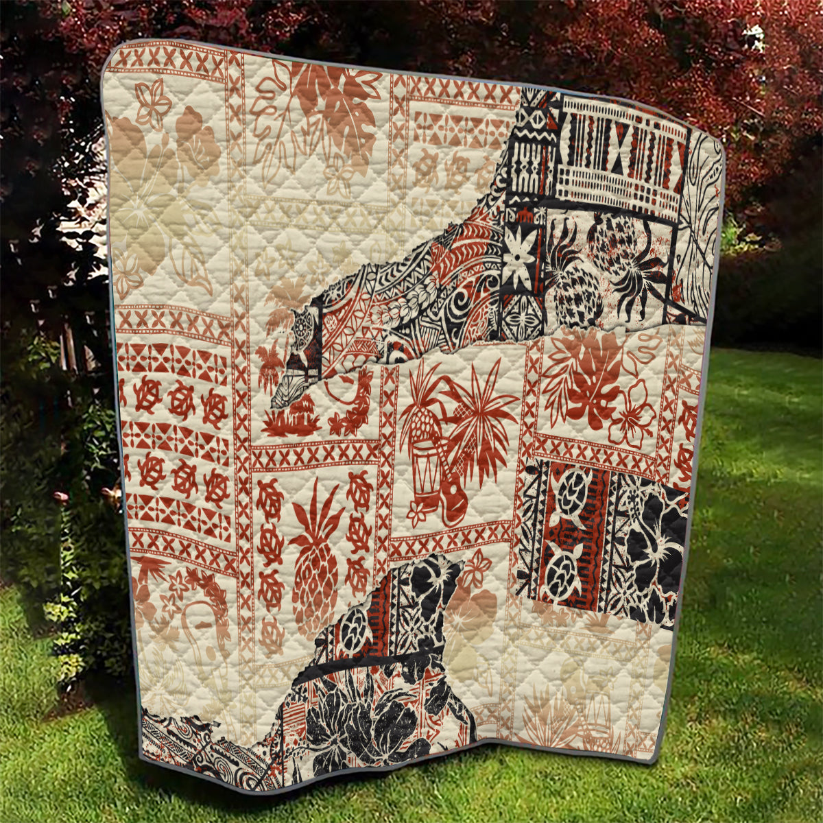 Beige quilted aloha tribal blanket with red, black, and white square and border prints