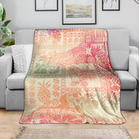 Pink ombre tropical blanket with patchwork floral and palm motifs, laid over couch
