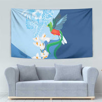 Blue hanging tapestry with hummingbird perched on green vine and white blossoms