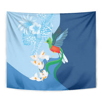 Close view blue tapestry with green bird, white floral spray, and orange petals