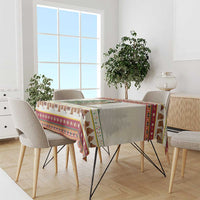 Multicolor holiday tablecloth draped on rectangular dining table with cow and folk border