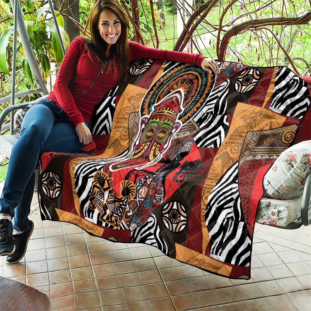 African motif quilt laid out on patio with zebra stripes, red accents, and central face artwork.