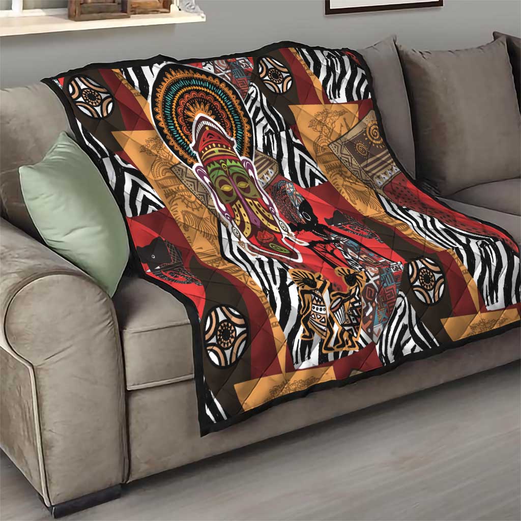 African motif quilt draped over sofa featuring zebra stripes, geometric blocks, and face medallion.