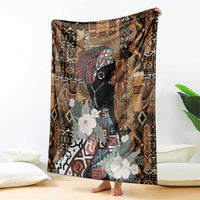 Brown blanket with black woman face silhouette, colorful geometric pattern, white flower details.