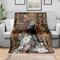 Brown tribal patterned blanket with black woman silhouette and large white flowers on sofa.