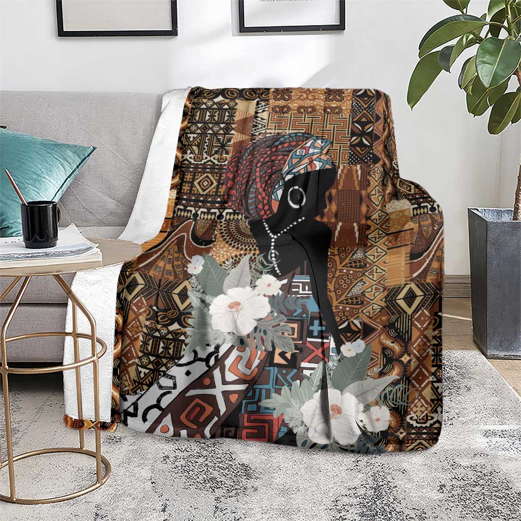 Brown tribal blanket with black woman silhouette, geometric motifs, and white flowers on floor.
