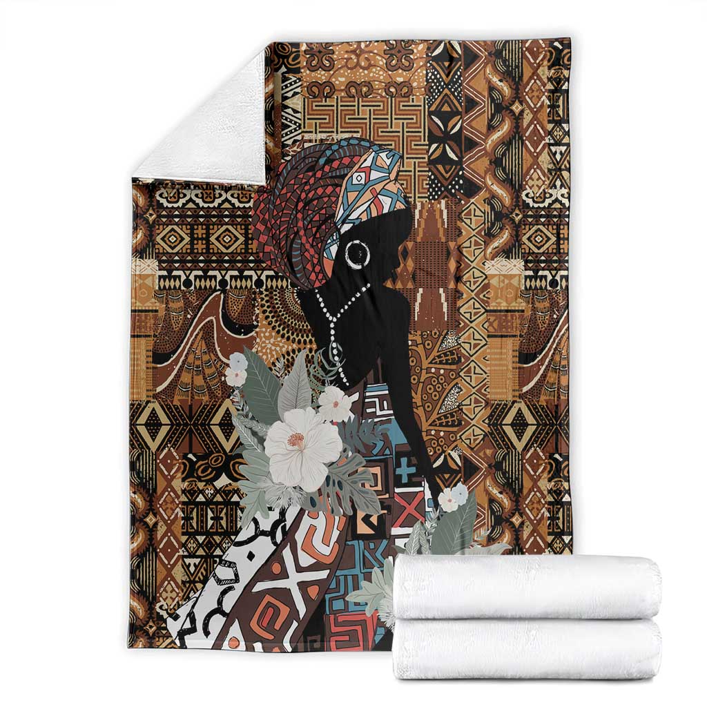 Brown blanket folded with black woman silhouette, geometric pattern, and white flowers.