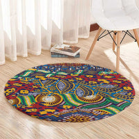Round tribal rug on light wood floor, blue animal-skin pattern with red and green