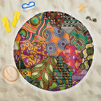 Round beach blanket with colorful African-inspired motifs and white fringed edge