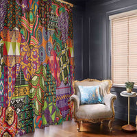 Multicolored ethnic motif curtain panels, fully draped beside a window and armchair.