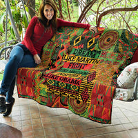 Multicolor quilt held open, showing geometric motifs and centered inspirational wording.
