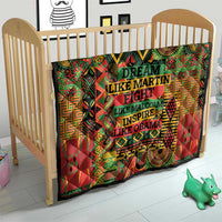 Multicolor quilt on a baby bed frame with tribal motifs and “DREAM” wording.