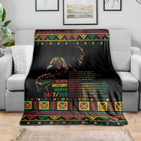 Black history blanket with colorful patterned border and bold text, spread on gray sofa