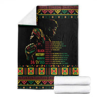 Black history blanket with colorful border and portrait graphic, folded with white towels