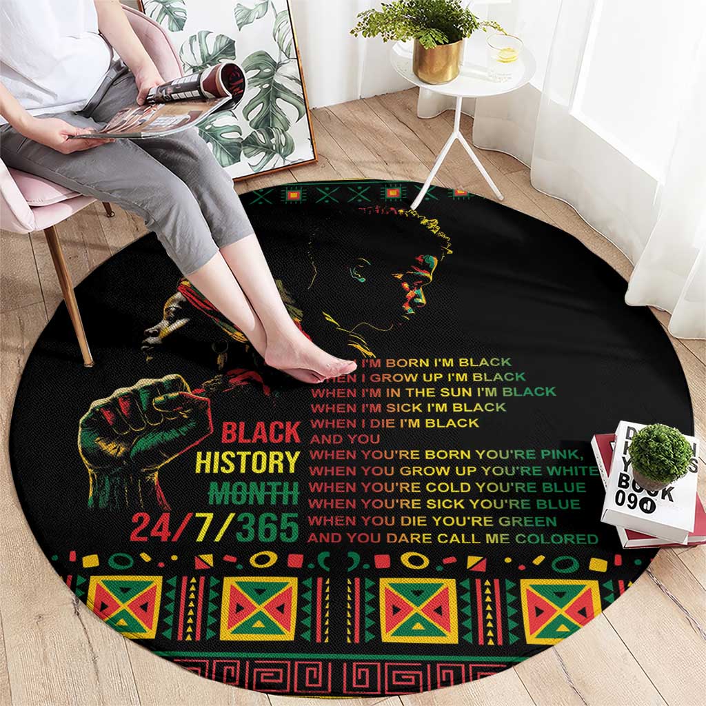 Black round rug with colorful face and bold slogan text across the center