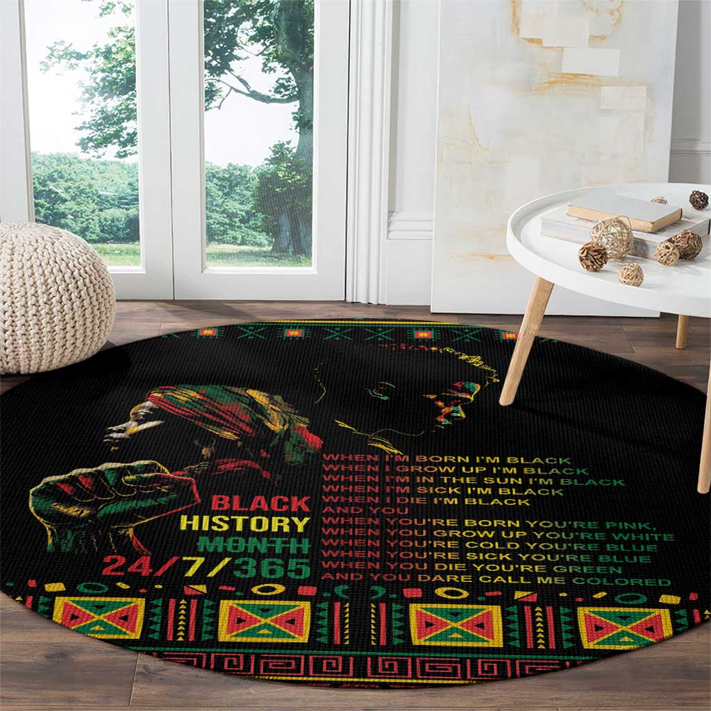 Black round rug featuring colorful face graphic, slogan text, and patterned edge