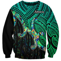 Green unisex sweatshirt with tribal pattern, Aotearoa text, and shell graphic, long sleeves